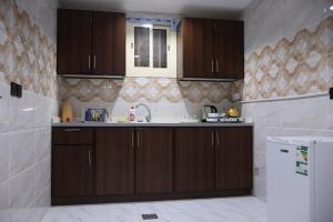 Al Qunfudhahجوهرة القنفذة的厨房配有棕色橱柜和水槽