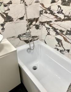 利耶帕亚Grīzupes apart的浴室铺有大理石瓷砖,配有白色浴缸。