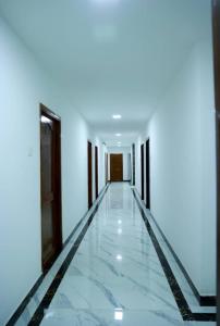 KottakupamParadise Golden Residency的一条空的走廊,有白色的墙壁和大理石地板