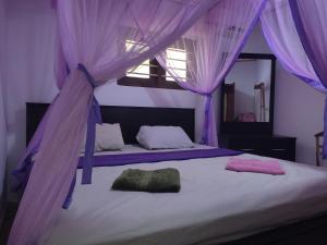 KamburugamuwaRed Rose Villa Mirissa的一间卧室配有两张紫色窗帘的床