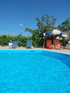 阿齐亚佩拉加克里塔日光公寓酒店的蓝色游泳池设有两把椅子和一把遮阳伞