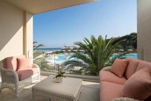 利尼亚诺萨比亚多罗Riviera Resort Hotel的阳台配有粉红色的椅子,享有海滩美景