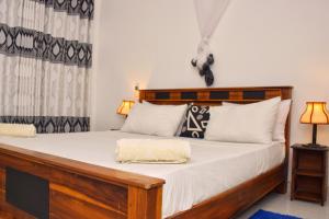锡吉里亚Sunrise Cottage的一间卧室配有一张带白色床单和枕头的木制床。