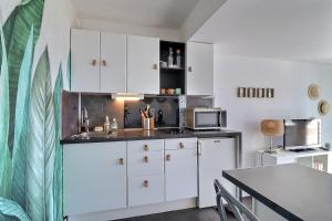 多维尔Cosy Deauville的厨房配有白色橱柜和桌子