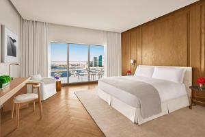 阿布扎比The Abu Dhabi EDITION的卧室配有白色的床、书桌和窗户。