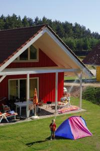 Groß QuassowCamping-und Ferienpark Havelberge的站在房子前帐篷旁的儿童