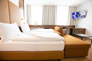 施韦夏特Das Reinisch Hotel & Restaurant的酒店客房配有一张带白色枕头的大床