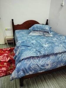 Kampung GurunHomestay D'Murni的一张带蓝色棉被和枕头的床
