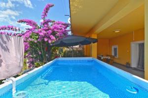 罗波里卡Apartment Miha的一座带紫色花卉和遮阳伞的游泳池