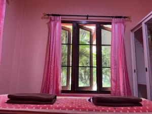 卡农快乐度假村 的卧室设有窗户和粉红色窗帘
