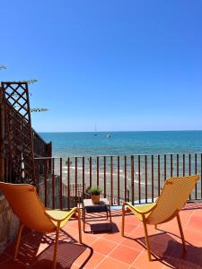 圣塔马里亚迪卡斯特Residenza Fontanelle-Beach Resort的俯瞰海滩的天井上配有2把椅子和1张桌子