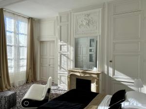 沙特尔Hôtel Particulier de Champrond的一间卧室配有一张床、一个壁炉和一个镜子