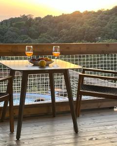 MontorgialiGlamping - Il Giardino di San Giorgio的阳台上的桌子和两杯葡萄酒