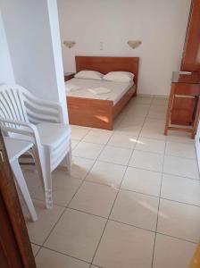 埃亚玛琳娜奈奇多乔治娜酒店的卧室配有1张床和1把椅子,铺有瓷砖地板。