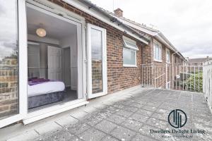 巴塞尔顿Purple Velvet - 2 Bed Home Spacious - Basildon Essex Upto 5 Guests, Free Wifi , Free Parking的阳台设有床和滑动玻璃门