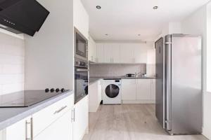 伦敦Lovely 3 bedroom flat in North London的厨房配有白色橱柜和不锈钢冰箱