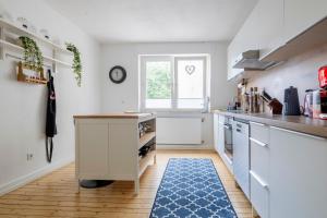 霍尔茨维克德Modernes Zuhause - Küche - Top Anbindung - High WLAN的厨房配有白色橱柜和蓝色地毯。