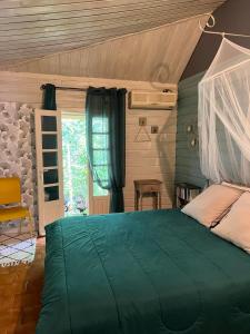 圣若瑟La Kaz LANGEVIN的一间卧室设有一张绿色的床和一个窗户。