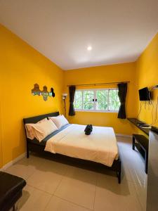 北革โรงแรมบ้านเพิ่มสุข อิมแพ็ค เมืองทอง的一间卧室设有一张黄色墙壁和窗户的床