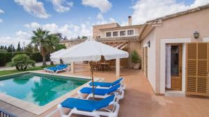 坎波斯Casa rural, finca rústica con piscina Cas Padrins de Campos, Mallorca的房屋旁的游泳池配有椅子和遮阳伞