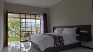 GubukklakahMountain Ecolodge的一间卧室设有一张大床和一个滑动玻璃门