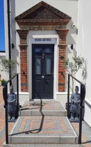 滨海克拉克顿Viva Guest House的大楼前有两座雕像的黑色门