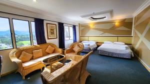 怡保园博会酒店的酒店客房带两张床、一张沙发和椅子。