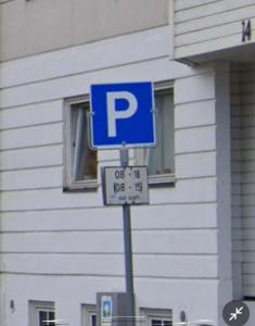 特隆赫姆Jennifers Place的建筑前一根杆上的蓝色停车标志