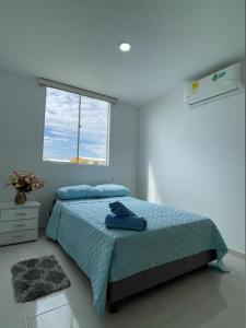 内瓦CB Somos AT HOME Apto cómodo e impecable con Aire Acondicionado的一间卧室配有一张带蓝色毯子的床和窗户。