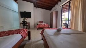 巴亚索拉诺Hotel Bahía Yubarta的酒店客房设有两张床和电视。