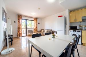 科拉雷侯Oasis Fuerteventura的厨房以及带白色桌椅的起居室。
