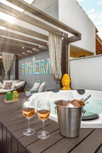 帕罗卡Pinheira Beach House com Jacuzzi的浴缸旁木桌旁的两杯葡萄酒