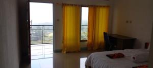英德FARILA LODGE的一间卧室设有床和黄色窗帘的窗户