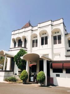JomblangHotel Candi Baru的前面有两块灌木的白色建筑