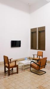 JomblangHotel Candi Baru的一间设有三把椅子、一张桌子和一台电视的房间