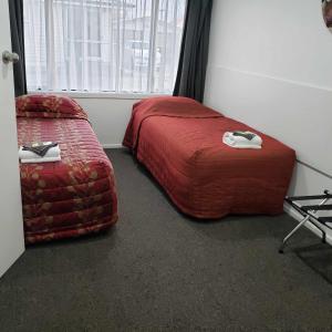 PahiatuaBrown Trout Motel的一间卧室配有红色的床和椅子