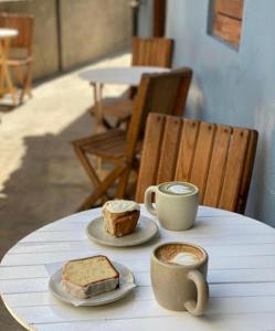 圣法兰西斯克DownTown Rooms San Pancho的一张桌子,上面放着两杯咖啡和一块蛋糕