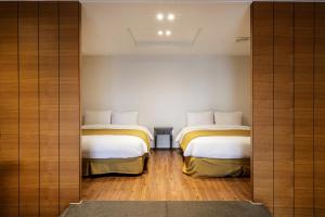 济州市Olle Resort & SPA的铺有木地板的小客房内的两张床