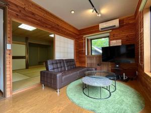 草津FOREST HOUSE的客厅配有真皮沙发和桌子