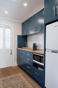 黑荒地Mount Booralee的厨房配有蓝色橱柜和白色冰箱
