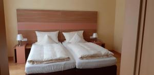 AylLinden's Pension-Restaurant的一间卧室配有两张带白色床单和枕头的床。