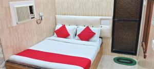 孟买Swapna International的一张带红色和白色枕头的床