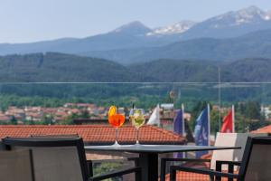 班斯科Ruskovets Thermal SPA & Ski Resort的阳台上的桌子上放着两杯葡萄酒