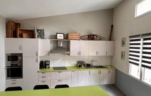 VertSéjour au vert的厨房配有白色橱柜和绿色台面