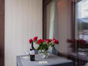 西维耶兹Apartment Rosablanche C51 by Interhome的一张桌子,上面放着玫瑰花瓶和一瓶葡萄酒
