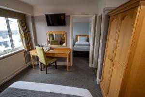 伯恩茅斯Commodore Hotel by Greene King Inns的酒店客房设有书桌和卧室。