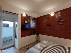 洛夫兰Apartment Tami with Swimming pool的一间卧室设有砖墙、一张床和电视