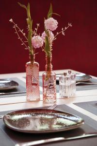 爱尔福特Hotel am Waldkasino的一张桌子,上面有盘子和花瓶,里面装有鲜花
