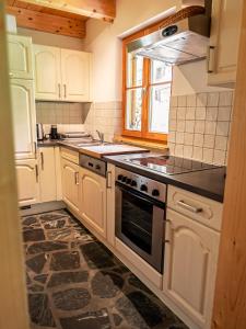 图拉彻霍赫Alpin-Hütten auf der Turracherhöhe - Haus Fuchs by S4Y的厨房配有白色橱柜和炉灶烤箱。