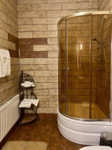 NizhnedneprovskЕДБУРГ Готельно-ресторанний комплекс的一间带玻璃淋浴和椅子的浴室